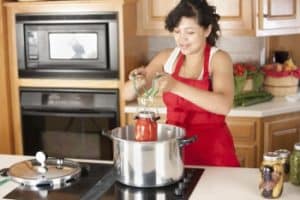 mujer con delantal rojo cocinando con olla express