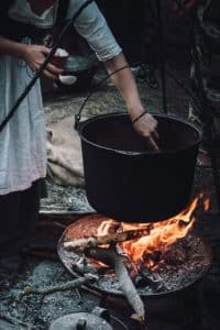 mujer cocinando con un horno holandés de color negro