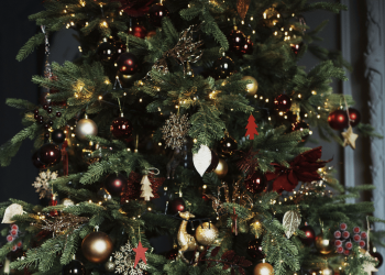 Primer plano de un árbol de Navidad con adornos navideños en tonos rojos y dorados.