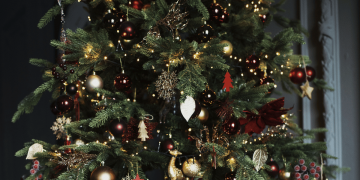 Primer plano de un árbol de Navidad con adornos navideños en tonos rojos y dorados.