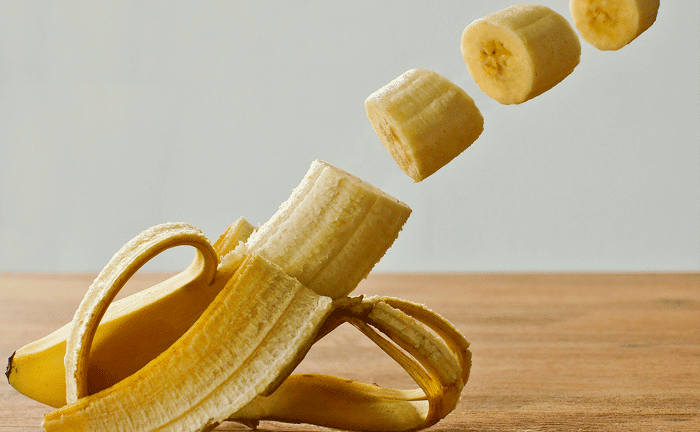 Un plátano abierto y cortado a trocitos en el aire.