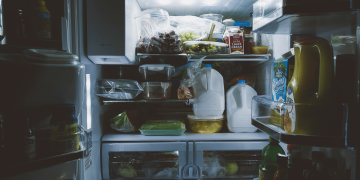 Un frigorífico muy lleno de comida con la puerta abierta.