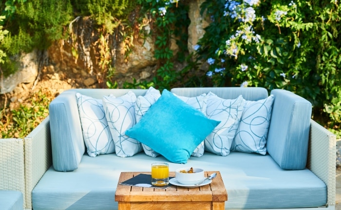 sofa de terraza con cojines azules y mesita de desayuno