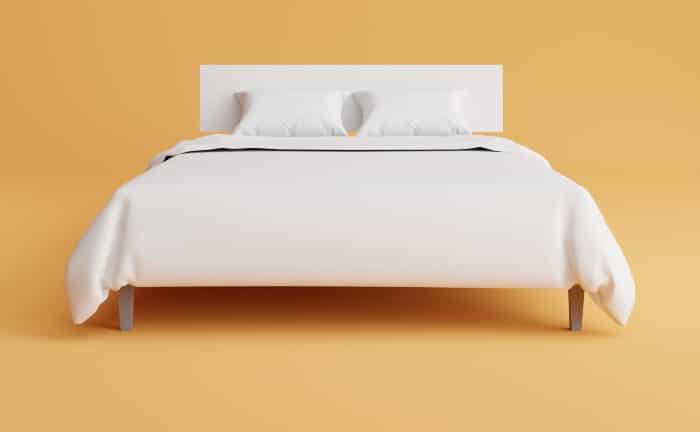 habitación naranja con cama blanca en el centro, con sábanas, cabecero y dos almohadas todo en blanco