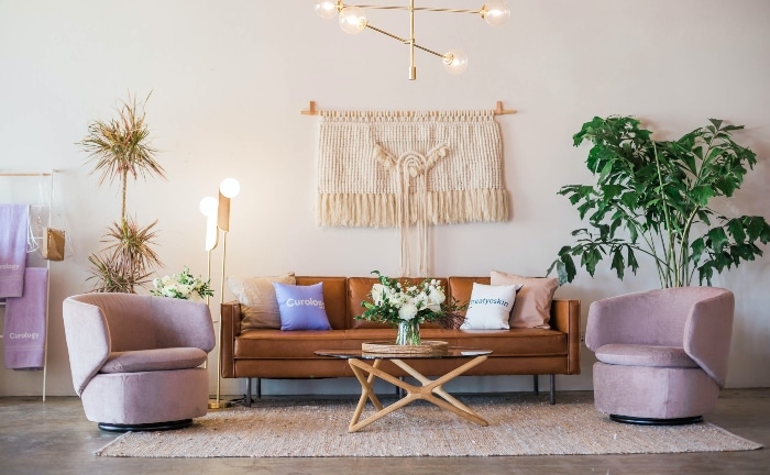 salón cin sofá marrón, complementos de fibras naturales como alfombra o colgante, mesa con plantas y cojines en crudos y morados