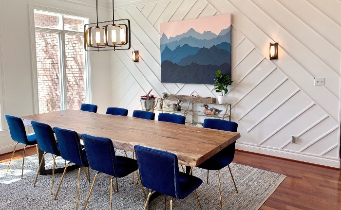 comedor con pared con panales, ventanal, sillas tapizadas en azul y mesa de madera rectangular