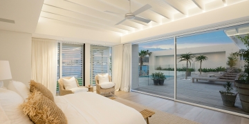 Habitación en tonos blancos, ventilador de techo incluido, con acceso a terraza con tumbonas