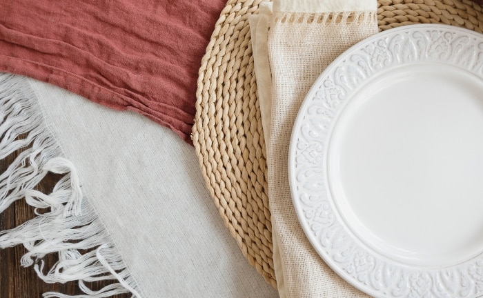 plato balnco sobre mantel individual de tejido natural y mantel de lino blanco son otro mantel rosado