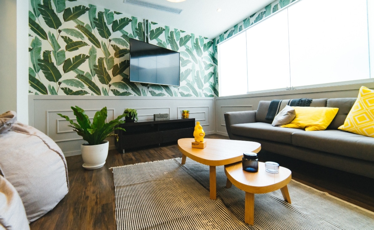 salón en madera y gris, con plantas y papel pintado de hojas verdes