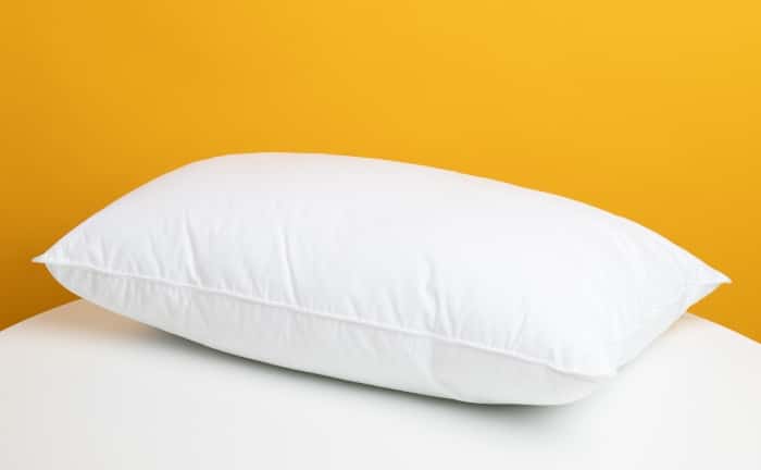 almohada blanca sin funda sobre colchón blanco en habitación amarilla