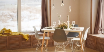 mesa de comedor en madera con cuatro sillas en tonos tierra y lámpara con bombillas colgantes