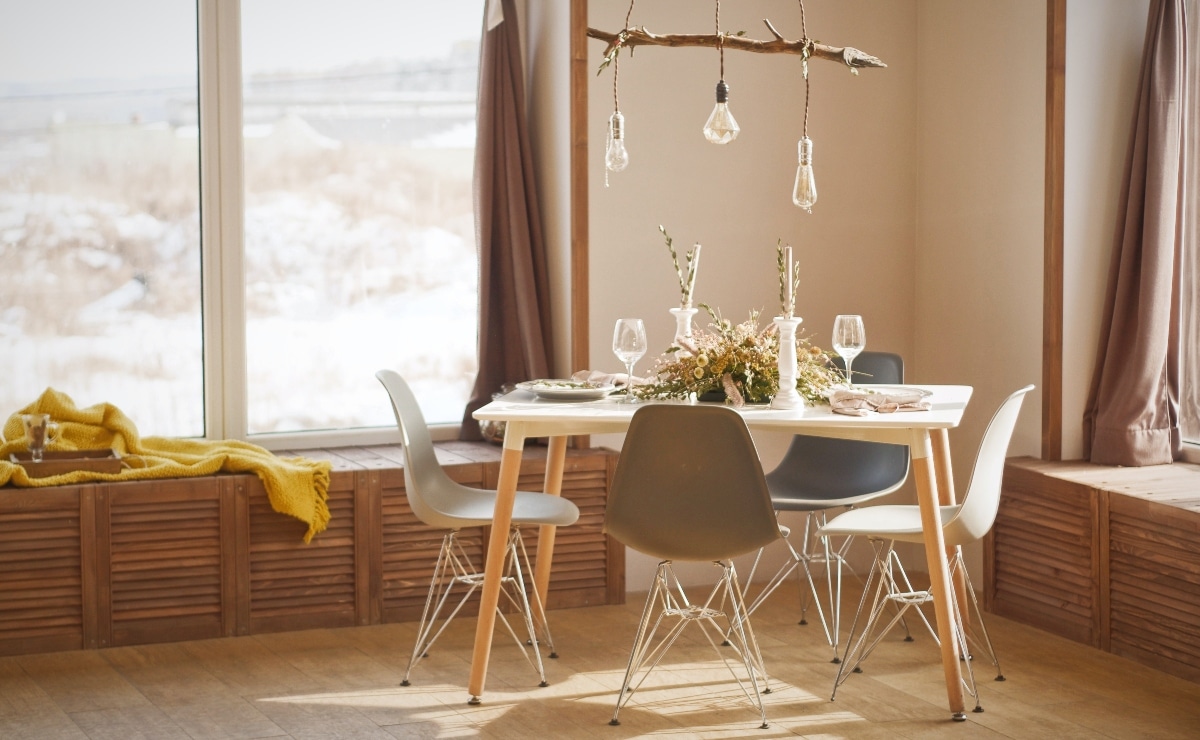 mesa de comedor en madera con cuatro sillas en tonos tierra y lámpara con bombillas colgantes