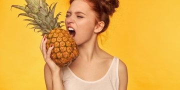 mujer comiendo fruta piña