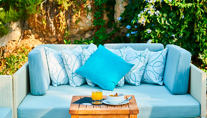 Terraza con sofá de mimbre y cojines azules